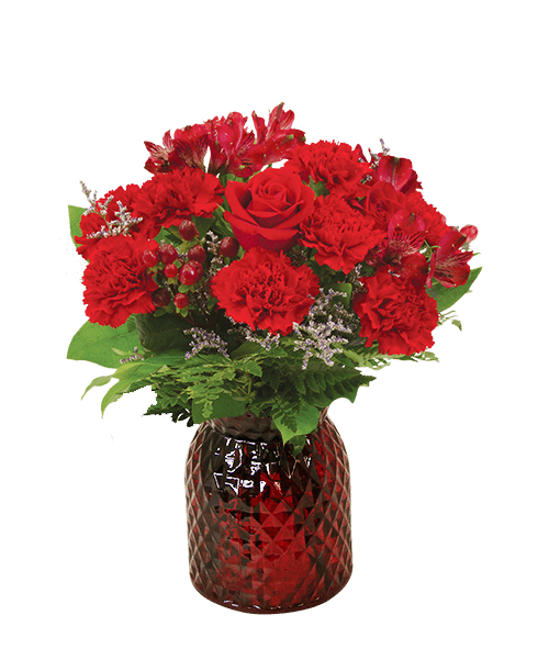 A 6.5 inchH red glass vase with a diamond pattern holds an all-around arrangement in reds including three roses, carnations, alstroemeria, hypericum, and caspia. 14 inchH x 11 inchW