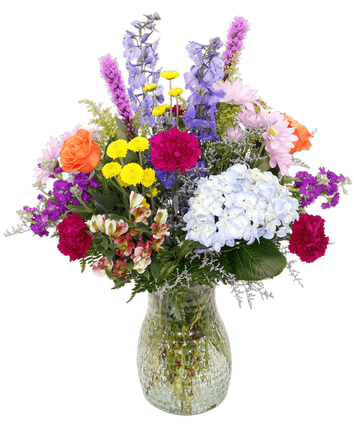 An 10 inch pebbled glass vase holds an all-around arrangement with two roses, delphinium, hydrangea, charmelia alstroemeria, stock, carnations, daisy poms, button poms, liatris, solidago, and caspia. 26 inchH x 19 inchW
