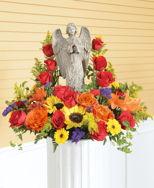 An all around arrangement from our Tuscan Funeral Collection, suitable to be sent to a funeral or memorial service, featuring a 15 inch praying angel keepsake with roses, sunflowers, lilies, carnations, viking poms, hypericum, statice, and solidago. 22 inchL x 21 inchW x 17 inchH