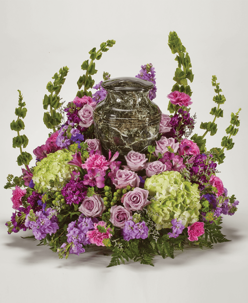 An all around arrangement from our Tranquil Funeral Collection, with roses, stock, Bells of Ireland, hydrangea, alstroemeria, stock, carnations, green button poms, statice, and caspia. Suitable for a funeral or memorial service with the option to display a special memento, a framed photo, an urn, or a candle. Overall 25 inchL x 24 inchW x 23 inchH 