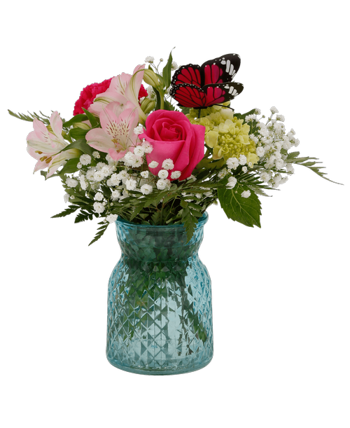 A 5.5 inchH blue glass vase with a diamond pattern holds an all-around arrangement with a mini green hydrangea, pink alstroemeria, a hot pink carnation, a pink rose, baby's breath, and includes a butterfly stick-in. Overall 10 inchH x 8 inchW