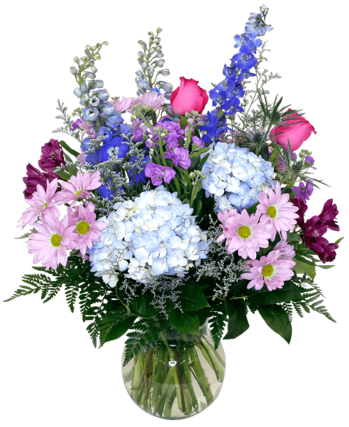 A 7-3/4 recycled glass vase holds an all-around arrangement with three roses, hydrangea, stock, delphinium, eryngium, alstroemeria, daisy poms, and caspia. 25 inchH x 16 inchW