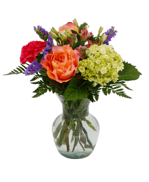 A 6.75 inch glass vase holds an all around arrangement with two orange free spirit roses, a mini green hydrangea, pink charmelia alstroemeria, a hot pink carnation, and purple statice. 12 inchH x 10 inchW