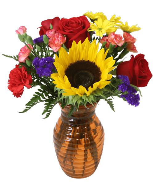 A 7.25 inchH orange glass vase with a horizontal design holds an all around arrangement with three red roses, a sunflower, a red carnation, yellow daisy poms, orange mini carnations, and purple statice. 14 inchH x 11 inchW