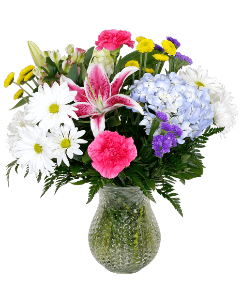 A 7 inch clear dimpled glass vase holds an all-around arrangement with a blue hydrangea, a mini green hydrangea, a stargazer lily stem, pink charmelia alstroemeria, hot pink carnations, white daisy poms, yellow button poms, and purple statice. 17.5 inchH x 14.5 inchW 