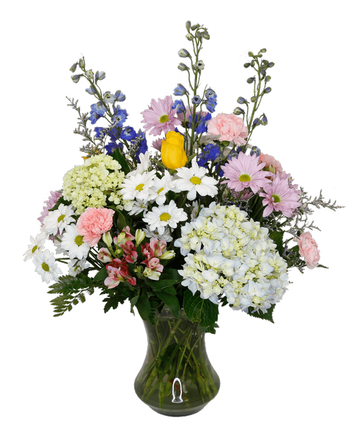 A 9.5 inch glass vase holds and all around arrangement with two yellow roses, blue hydrangea, mini green hydrangea, pink charmelia alstroemeria, blue delphinium, pink carnations, white and lavender daisy poms, and caspia. Overall 28 inchH x 21 inchW