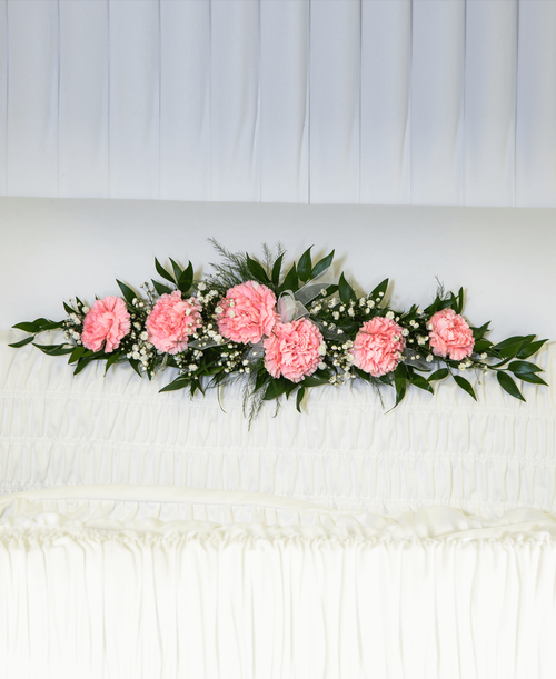 A ledgepiece from our Traditional Funeral Collection to be placed inside the casket and suitable to be displayed at a funeral or memorial service, is designed with carnations and babies breath. 21 inchL x 7 inchW