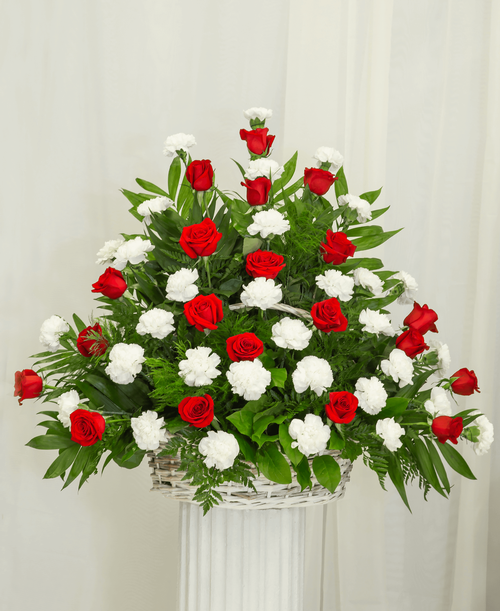 A one-sided arrangement from our Classic Rose & Carnation Funeral Collection, suitable to be sent to a funeral or memorial service, with roses and carnations designed in a oval basket. 32 inchH x 36 inchW