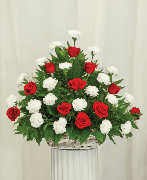 A one-sided arrangement from our Classic Rose & Carnation Funeral Collection, suitable to be sent to a funeral or memorial service, with roses and carnations designed in a oval basket. 25 inchH x 28 inchW