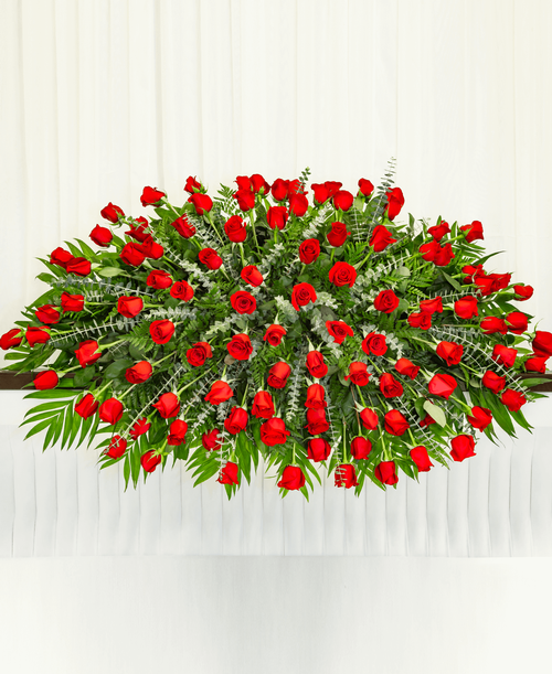 A full casket spray from our Beloved Funeral Collection designed with roses and assorted greens. 60 inchL x 30 inchW