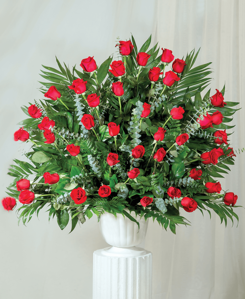 A one-sided arrangement from our Beloved Funeral Collection, suitable to be sent to a funeral or memorial service, with roses and assorted greens designed in a 9.5 inch pedestal urn. 37 inchH x 37 inchW