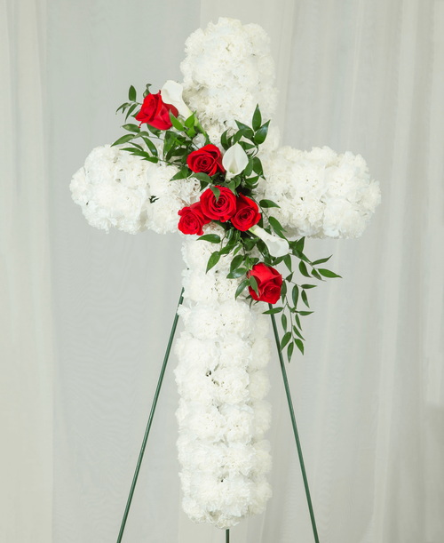 A 30 inch cross from our Beloved Funeral Collection, suitable to be sent to a funeral or memorial service, is designed using carnations, roses, and calla lilies. 34 inchL x 20 inchW - Displayed on a 54 inch Easel