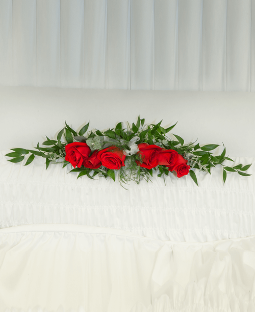 A ledgepiece from our Beloved Funeral Collection to be placed inside the casket and suitable to be displayed at a funeral or memorial service, is designed with roses and assorted greens. 25 inchL x 5 inchW
