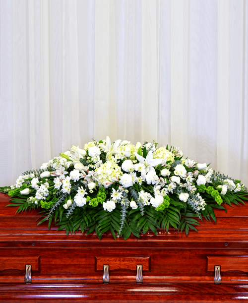 A full casket spray from our Celestial Funeral Collection with roses, hydrangea, stock, lilies, carnations, cushion poms, alstroemeria, bells of Ireland, and assorted greens. 64 inchL x 48 inchW
