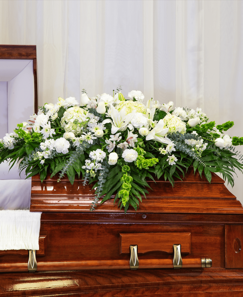 A half casket spray from our Celestial Funeral Collection with roses, hydrangea, stock, lilies, carnations, cushion poms, alstroemeria, bells of Ireland, and assorted greens. 52 inchL x 46 inchW