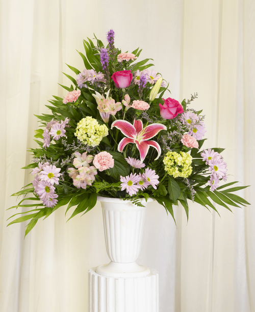 A one-sided arrangement from our Pink Elegance Funeral Collection, suitable to be sent to a funeral or memorial service, with a lily, two roses, mini hydrangea, liatris, alstroemeria, carnations, daisy poms, and caspia designed in a 11-1/4 inch urn. 35 inchH x 26 inchW