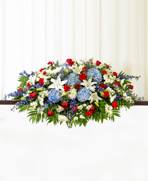 A full casket spray from our Patriotic Funeral Collection with roses, hydrangea, lilies, delphinium, stock, carnations, football mums, cushion poms, eryngium, and assorted greens. 60 inchL x 36 inchW