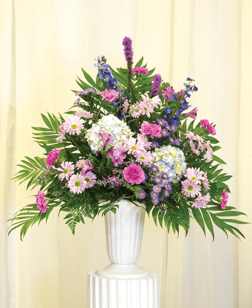 A one-sided arrangement from our Tranquil Funeral Collection, suitable to be sent to a funeral or memorial service, hydrangea, delphinium, liatris, daisy poms, carnations, caspia, purple statice, and assorted greens designed in a 11-1/4 urn. 34 inchH x 26 inchW