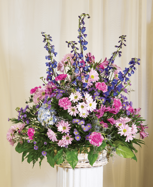 A basket arrangement from our Tranquil Funeral Collection, suitable to be sent to a funeral or memorial service, with hydrangea, delphinium, stock, alstroemeria, daisy poms, carnations, eryngium, purple statice, caspia, and assorted greens designed in a basket. 25 inchH x 25 inchW; Overall 34 inchH
