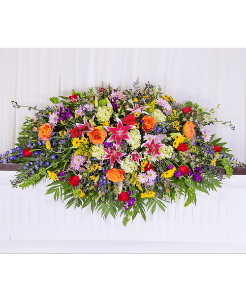 A full casket spray from our English Garden Funeral Collection, with roses, hydrangea, delphinium, stock, lilies, alstroemeria, bells of Ireland, daisy poms, viking poms, solidago, caspia, and assorted greens. 60 inchL x 28 inchW