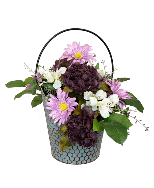 A 11.25 inchH teal honeycomb bucket holds an all around silk arrangement with purple peonies, white alstroemeria, lavender gerbera daisies and purple blossoms. Overall 16.5 inchH x 24 inchW