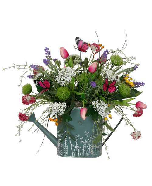 A 15.75 inch x 3.25 inch x 9 inch wildflower and dragonfly designed watering can holds an all around arrangement with pink tulips, green ball flowers, magenta allium, white Queen Annes lace, lavender, yellow berries, and four butterflies. Overall 21.5 inchH x 21 inchW x 17 inchL