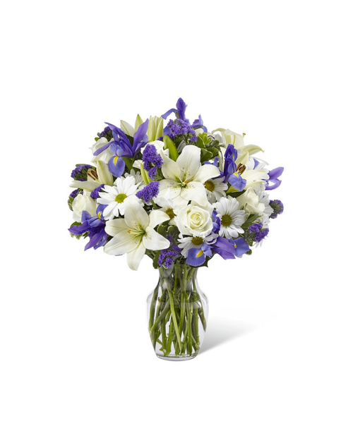 The Sincere Respect™ Bouquet is a soft and lovely way to express your condolences for your special recipient's loss. Blending together white roses, white traditional daisies, and white Asiatic Lilies with pops of blue iris and purple statice, this gorgeous bouquet is set to offer wishes of peace and caring kindness during this time of grief and loss. Presented in a classic clear glass vase, this fresh flower arrangement is a wonderful way to commemorate a life well lived. 20 inchHx17 inchW