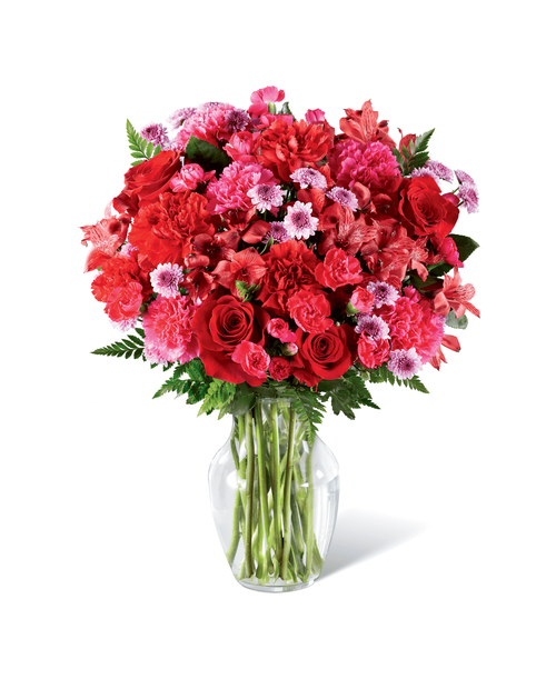 Brilliantly rosy in color, this fresh flower arrangement is out to have your recipient tickled pink with delight. Hot pink carnations and mini carnations start as the color base surrounded by the deeper red hues of roses, carnations, and Peruvian Lilies, accented with the lighter shade brought on by lavender button poms contrasting with assorted greens for a full and lush effect. Presented in a classic clear glass vase, this eye-catching flower bouquet is a standout thank you, thinking of you, or happy birthday gift. Approx. 17 inchH x 14 inchW.