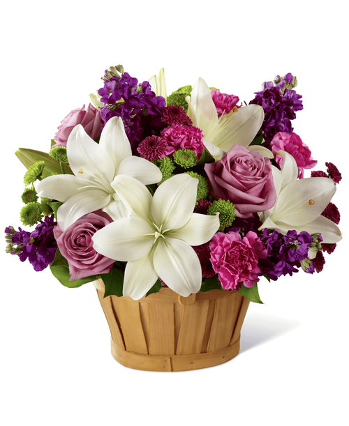A sweet treat of beauty to get your recipient focused on all the magic that life can offer each day, this fresh flower arrangement is a gift they will always remember. White Asiatic Lilies are clean and bright against a berry colored back drop of purple gilly flower, hot pink carnations, green button poms, purple button poms, lavender roses, and lush greens. Arranged lovingly in a rectangular woodchip basket to give it a casual, yet sweet appeal, this fresh flower bouquet is set to create a wonderful birthday, thank you, or get well gift! Approx. 14 inchH x 15 inchW.