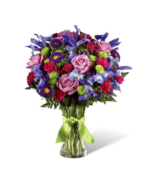 Share a world blooming in brilliant color and undeniable texture with this frilly and fun fresh flower bouquet . Blue iris, burgundy mini carnations, green button poms, lavender carnations, purple matsumoto asters, lavender roses, and lush greens mingle together to create a fascinating display. Presented in a modern clear glass vase tied with a lime green satin ribbon at the neck, this gift of flowers is a special surprise your recipient will love. Approx. 18 inchH x 14 inchW.