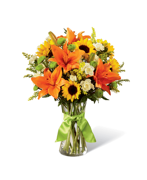 Speaking to rolling hills, blue skies, and time to breathe and relax, this sunlit bouquet is set to have your recipient finding joy in nature's beauty and light. Mini sunflowers, orange Asiatic Lilies, yellow mini carnations, green button poms, yellow solidago, and lush greens are arranged perfectly in a classic clear glass vase tied at the neck with a lime green satin ribbon. A simply gorgeous way to celebrate a birthday, say thank you, or send your warmest wishes for any of life's special moments! Approx. 17 inchH x 14 inchW.