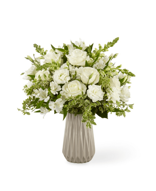A classic combination of ivory blooms and luscious greens make up our Serenity Bouquet. Comprised of white roses, double and snapdragons within a soft gray ceramic vase, this bouquet shines with beauty and elegance. Give this arrangement to add a divine and serene touch to wherever its placed. 18 inchHx16 inchW