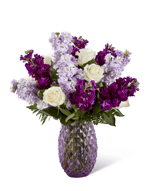 FTD proudly presents the Better Homes & Gardens Sweet Devotion Bouquet. Purple is a shade that captivates the imagination and inspires, with it's fascinating cool shades of light and dark. Bringing together a collection of purple's finest blooms, this enchanting bouquet offers a combination of the swirling petals of lavender roses, the fragrant stalks of purple and lavender gilly flower, and purple statice accented with clusters of green button poms and lush greens. Arranged to perfection within an attractive keepsake purple glass vase, this gorgeous flower bouquet is ready to create a special birthday, anniversary, or thinking of you moment! Approx. 20 inchH x 17 inchW