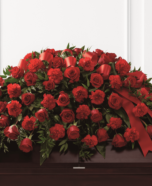 The FTD Dearly Departed Casket Spray bursts with the love and passion that the deceased had for their life and loved ones. Rich red roses and carnations are gorgeously arranged amongst lush greens and accented with a red satin ribbon to create the ideal adornment for their casket at their final farewell service. 40 inchW x 26 inchD
