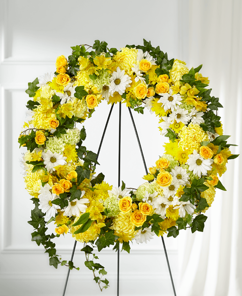 Whether yellow was their favorite color or it captures the essence of their radiance, a ring of bright blooms thoughtfully displays your sentiment. Our Golden Remembrance Wreath is composed of spray roses, daisy pompons, carnations and more. Each flower is selected t beautifully accent one another and the love you are sending. 
Wreath is approximately 24 inch in diameter 