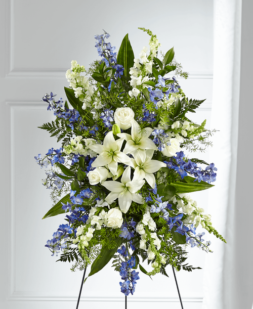 A collection of bold blue flowers shares a tribute that words cannot express. Designed with lilies, roses, delphinium and snapdragons our Faithful Friend Standing Spray is a grand gesture t express kindness and solace t a loved one while they are remembering the life they cherished s much. 
- Details:
Good spray is approximately 34 inchH x 23 inchW 
Better spray is approximately 36 inchH x 22 inchW 
Best Spray is approximately 38 inchH x 24 inchW