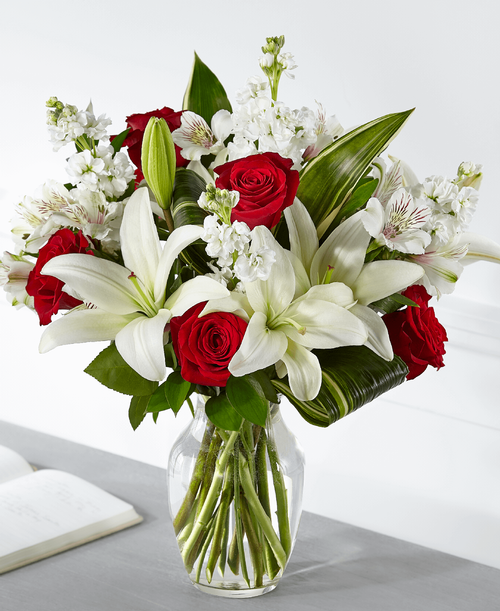 Elegantly crafted with a stunning mix of red and white blooms, our Loving Respect Bouquet reminds those you care about that you are thinking of them. Our local florists design roses and lilies together t convey your comfort and love. While this arrangement is perfectly sweet in size, it is best suited for a small table, or within a home or residence. 
Good bouquet is approximately 19 inchH x 15 inchW 
Better bouquet is approximately 19 inchH x 16 inchW 
Best bouquet is approximately 20 inchH x 18 inchW 