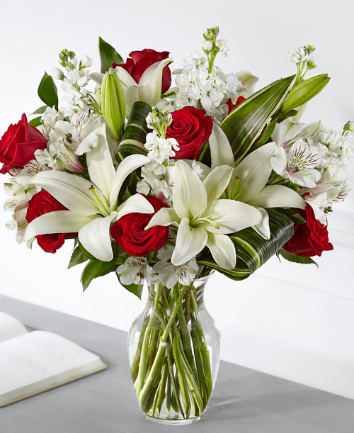 Elegantly crafted with a stunning mix of red and white blooms, our Loving Respect Bouquet reminds those you care about that you are thinking of them. Our local florists design roses and lilies together t convey your comfort and love. While this arrangement is perfectly sweet in size, it is best suited for a small table, or within a home or residence. 
Good bouquet is approximately 19 inchH x 15 inchW 
Better bouquet is approximately 19 inchH x 16 inchW 
Best bouquet is approximately 20 inchH x 18 inchW 