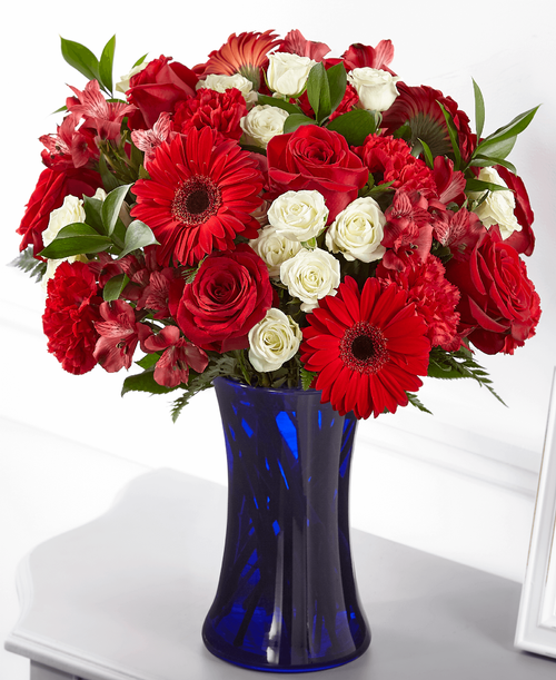 The combination of red, white and blue pays patriotic tribute t the heroes in our lives wh have passed. Our Hearts Embrace bouquet is designed with roses, gerbera daisies, alstroemeria and carnations in a bold blue vase t share a gesture of healing respect. 
Good bouquet is approximately 16 inchH x 14 inchW 
Better bouquet is approximately 17 inchH x 15 inchW
Best bouquet is approximately 18 inchH x 16 inchW 