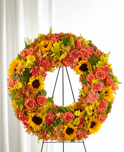 Share your sympathies with a stunning harvest wreath that both celebrates the season and their beautiful life. The vibrant shades of fall are curated with a collection of sunflowers, dianthus and roses in our Autumnal Memories Wreath. Each stunning bloom delivers your love and reverence with this timeless sympathy tribute. 
Wreath is approximately 26 inch in diameter 