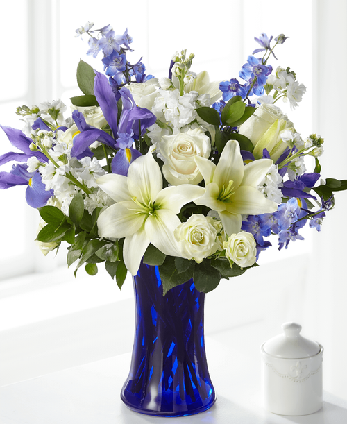 Accented by a deep blue vase, our Calming Comfort Bouquet is crafted with iris, lilies, stock and delphinium. This unique mix of blue and white flowers makes a well-suited tribute t send t those memorializing the loss of a male or someone wh had a soothing presence. While this arrangement is perfectly sweet in size, it is best suited for a small table or in a home. 
Good bouquet is approximately 17 inchH x 15 inchW 
Better bouquet is approximately 18 inchH x 16 inchW 
Best bouquet is approximately 19 inchH x 17 inchW 